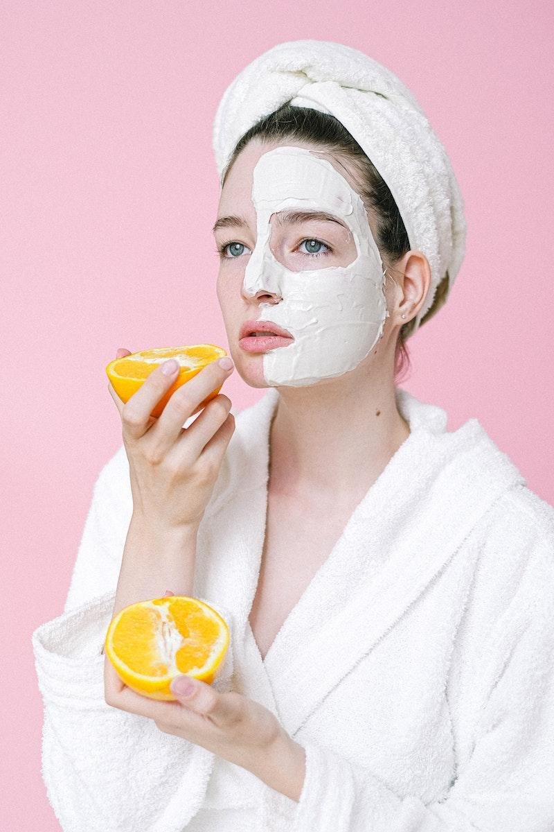 Woman holding oranges with an antioxidant face mask on her skin