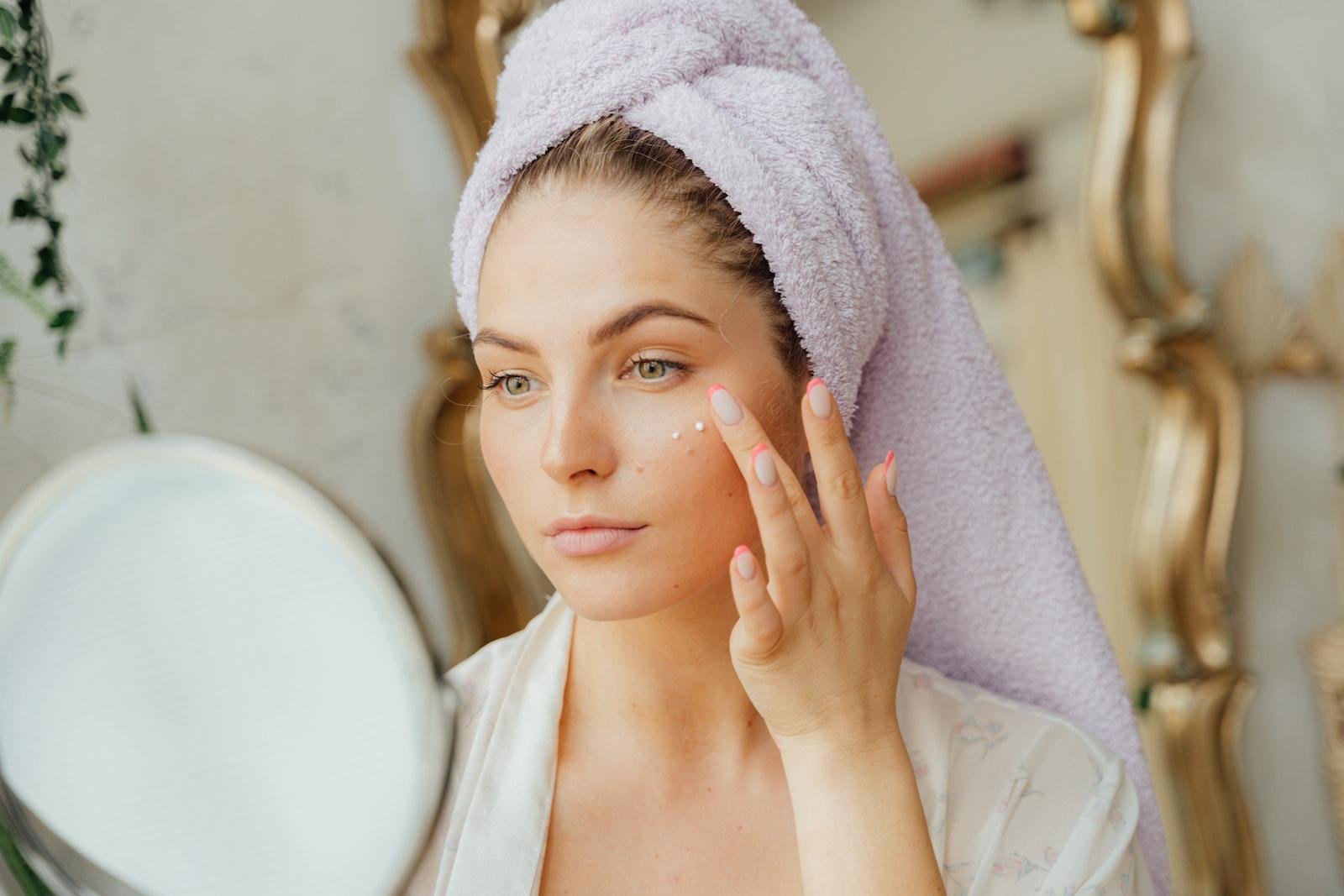 Woman With Head Towel Applying Face Cream for dry or dehydrated skin