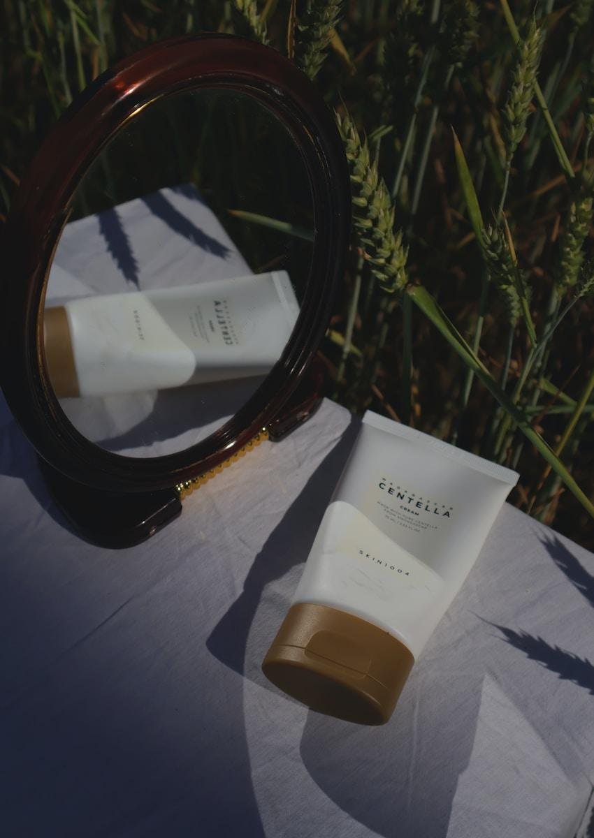 a close up of a table with a mirror and a tube of centella asiatica cream